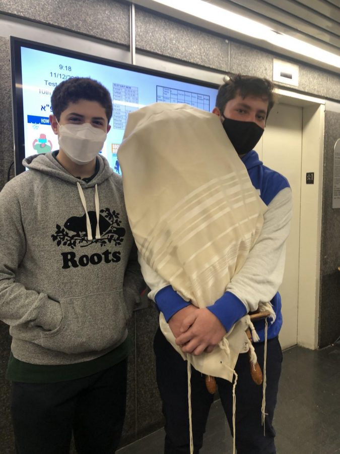 Ari Porter ‘23 and Nathan Haber ‘23 bringing a Torah from one minyan to another.